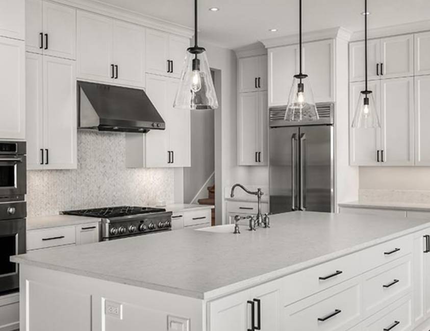 Modern kitchen with white cabinets, stainless steel appliances, and pendant lights